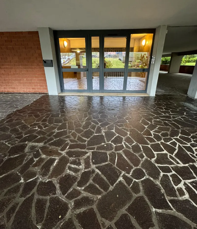 Ingresso condominiale con pavimento in pietra appena lavato