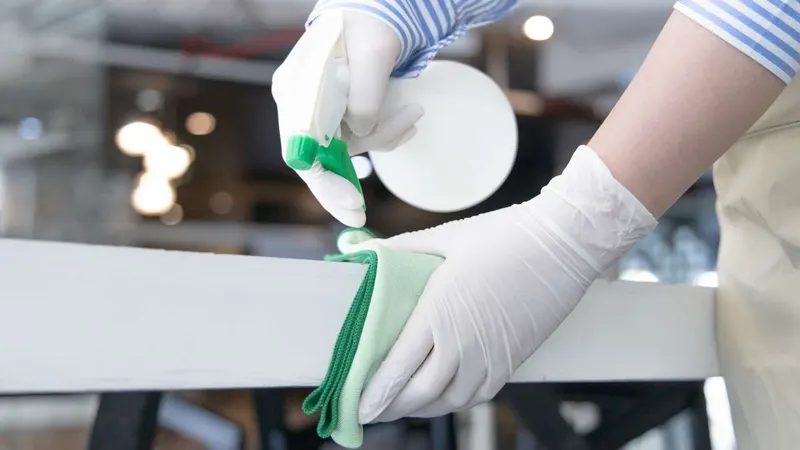 Operatrice che pulisce una superficie con panno in microfibra